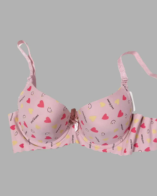 Pink bra with heart and smiley face patterns on a gray background
