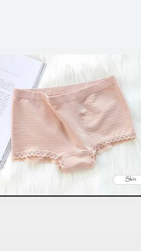 Pink lace-trimmed underwear on a white surface with a blurred background