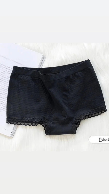 Black lace-trimmed shorts on a white surface with a book in the background