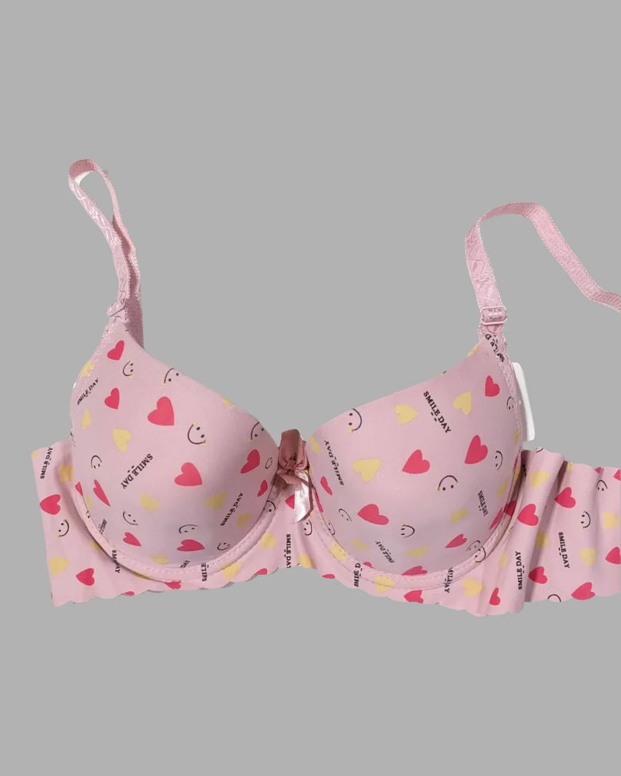 Pink bra with heart and smiley face patterns on a gray background