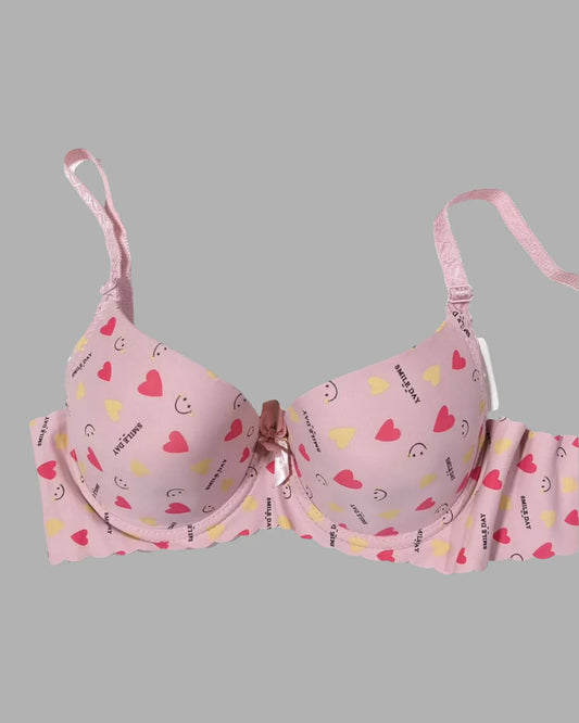 Pink bra with heart and smiley face patterns on a gray background